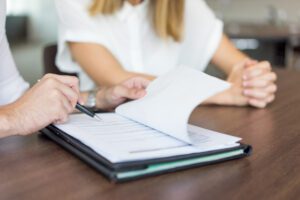 hands of male executive showing contract to female partner at meeting